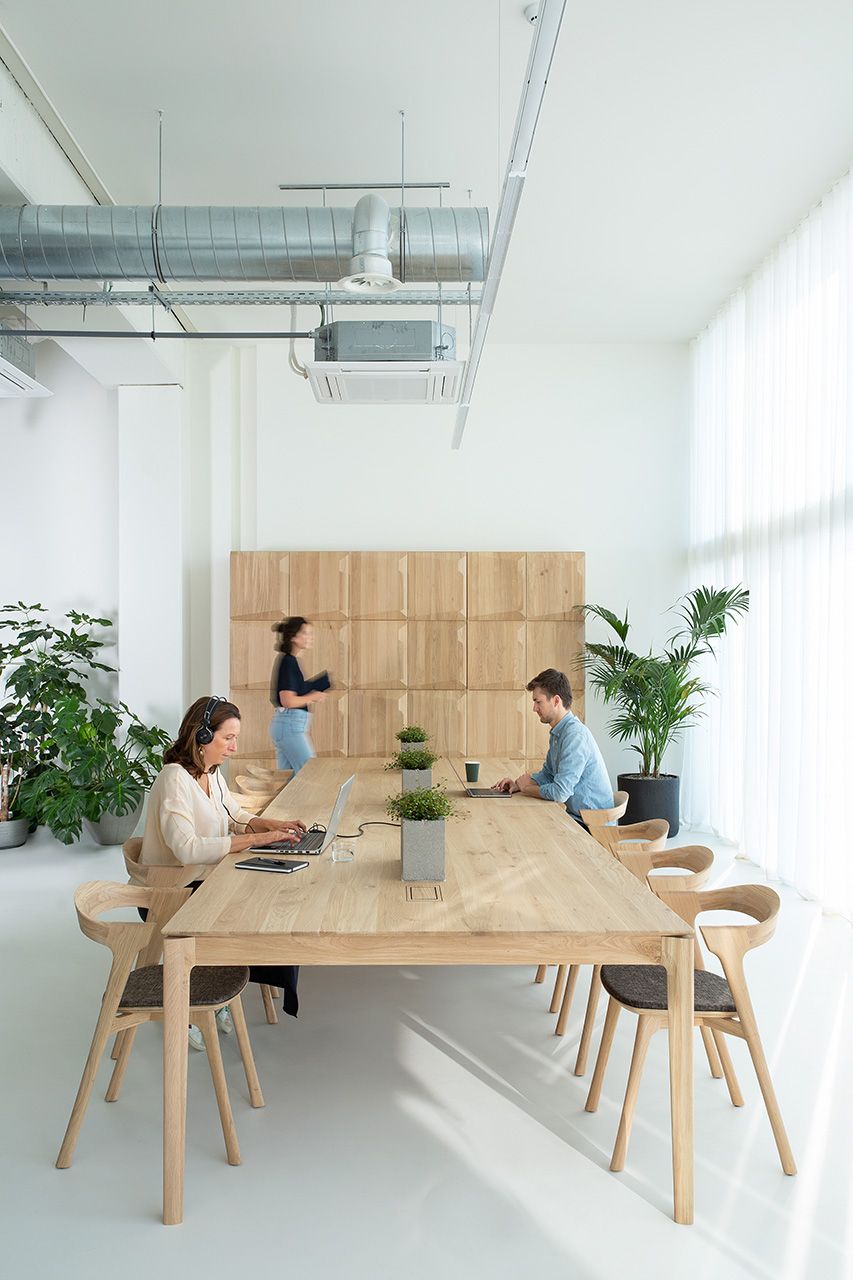 Bok Cowork Schreibtisch von Ethnicraft im modernen Büro mit Personen an Laptops und Pflanzen.