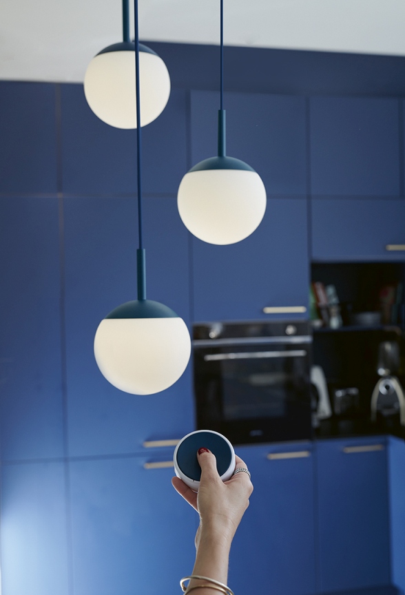 Mooon Triple Pendelleuchte von Fermob in Blau über Küchentisch mit Fernbedienung zur Lichtsteuerung.