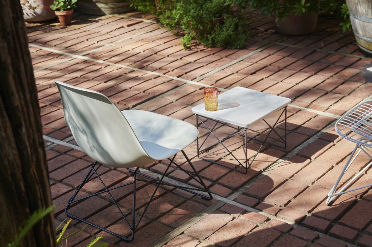 Vitra Eames Fiberglass Chair LSR in Weiß mit schwarzem Untergestell im Garten.
