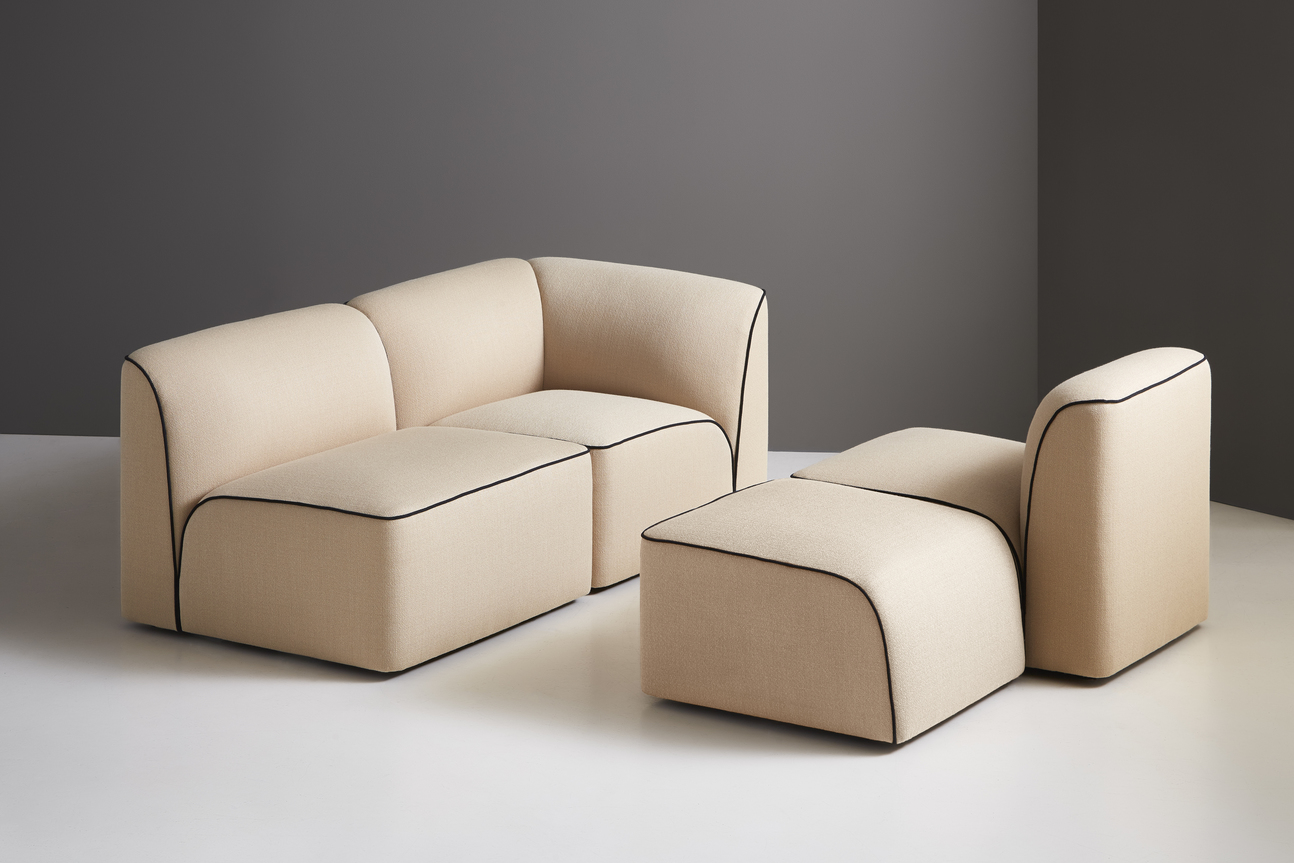 Beige modulare Eckcouch mit schwarzem Keder und passendem Hocker für modernes Wohnzimmer.