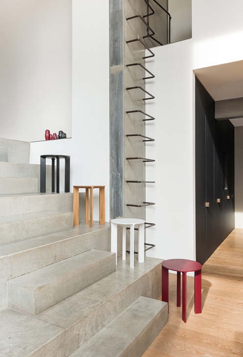 Hans Hocker Schönbuch: Mehrere farbige Holzhocker auf einer Treppe in einem modernen Interieur. Designhocker für Wohnraum.
