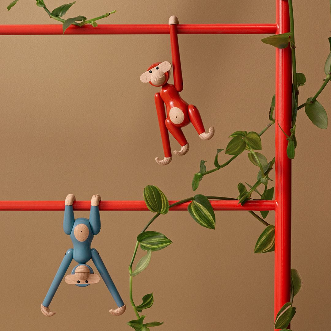 Buntes Affe Mini Holzfiguren Set von Kay Bojesen an rotem Regal mit grünen Pflanzen.