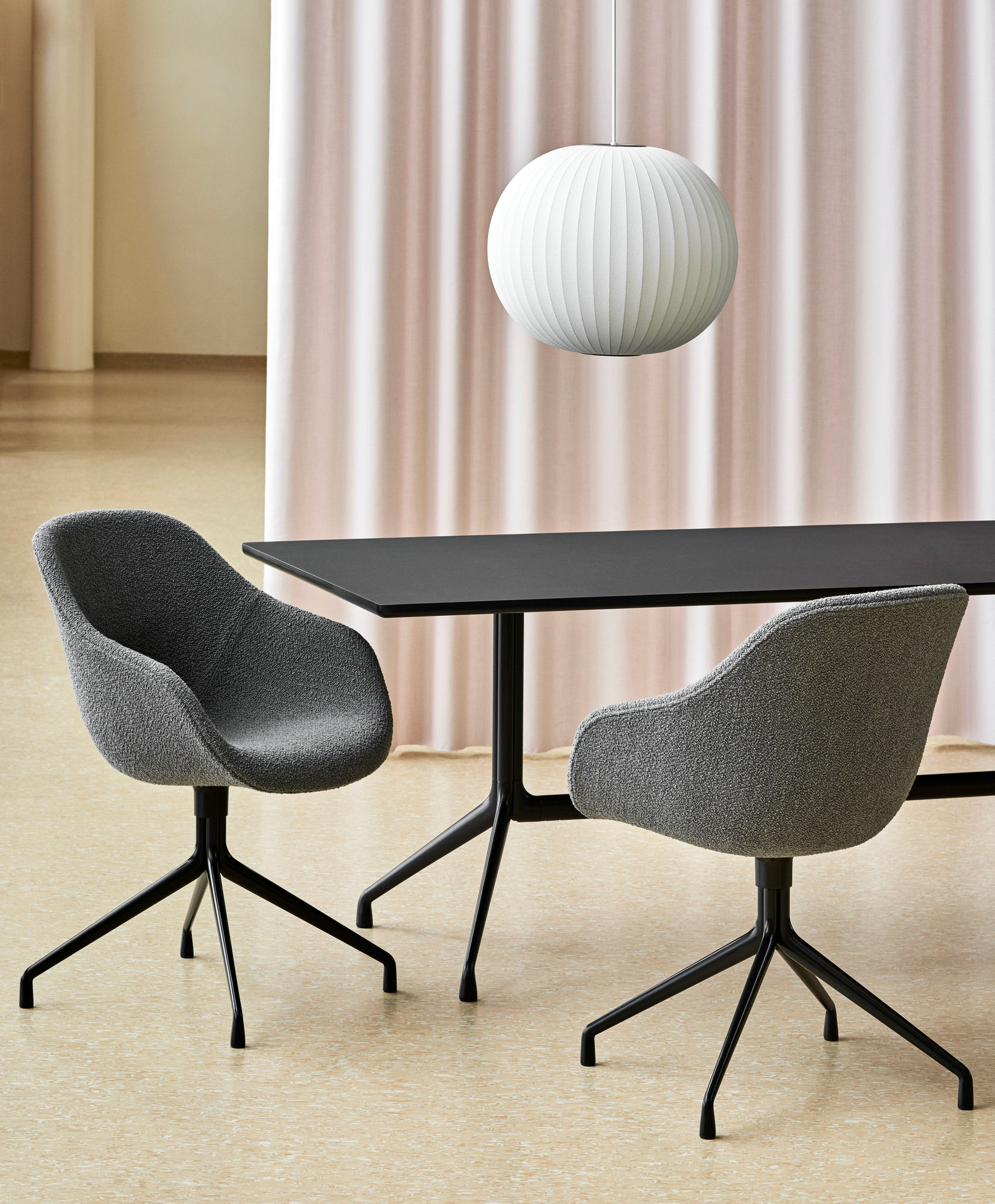 Zwei graue About a Chair AAC 121 Soft Duo Stühle von Hay an schwarzem Tisch.