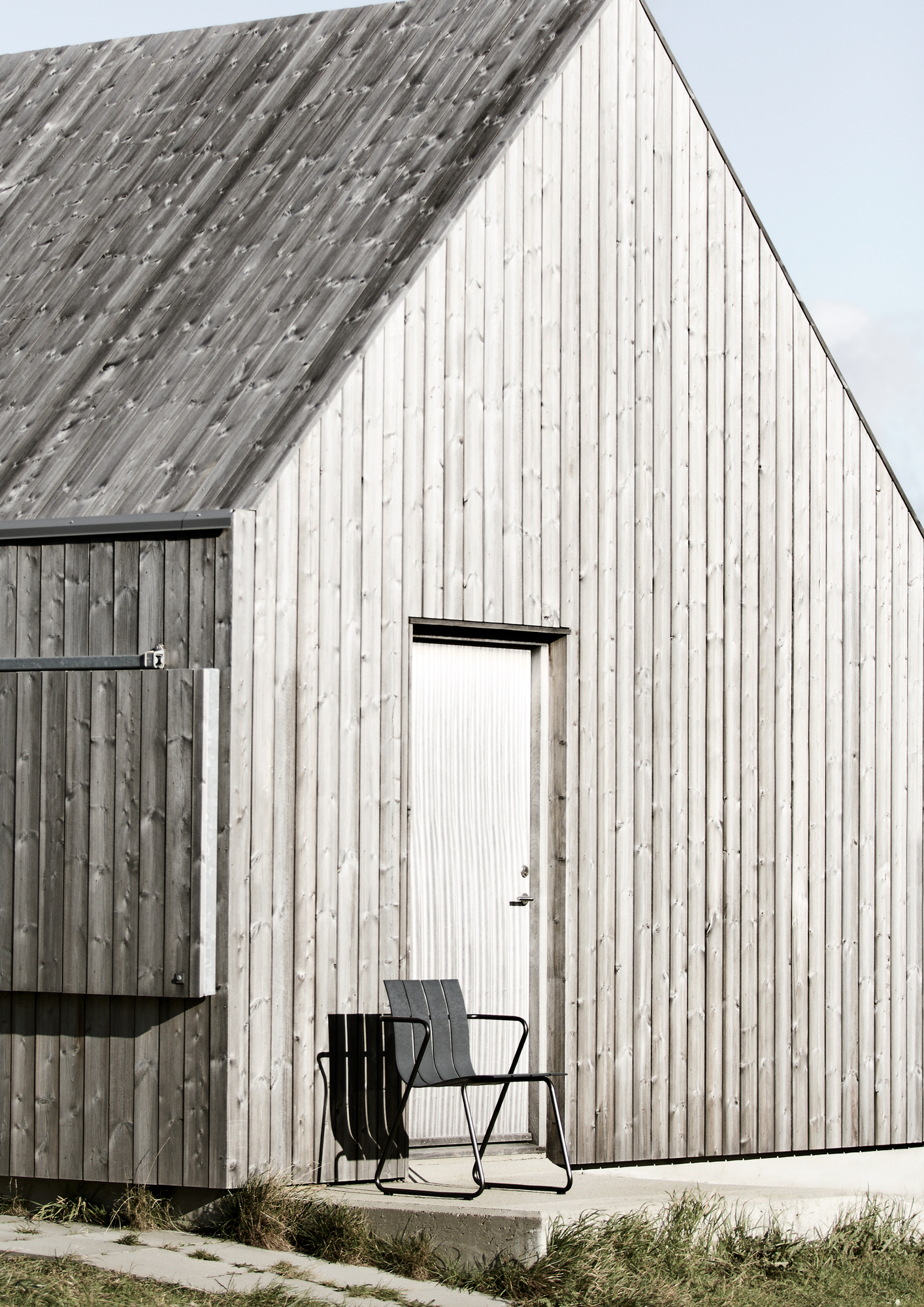 Ocean Chair von Mater vor einem modernen Holzhaus, minimalistisches Design für den Außenbereich.