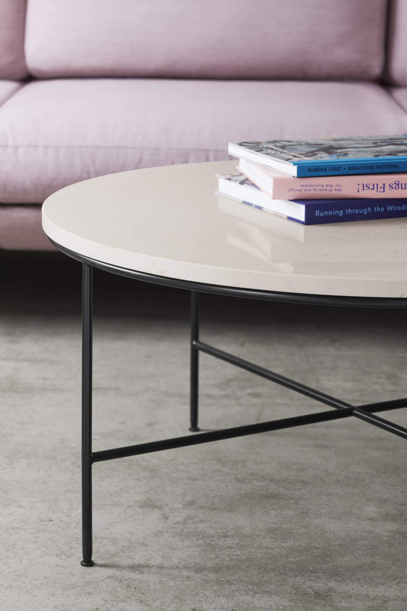 Fritz Hansen Couchtisch Planner mit runder, heller Tischplatte und schwarzem Metallgestell, Bücher darauf.