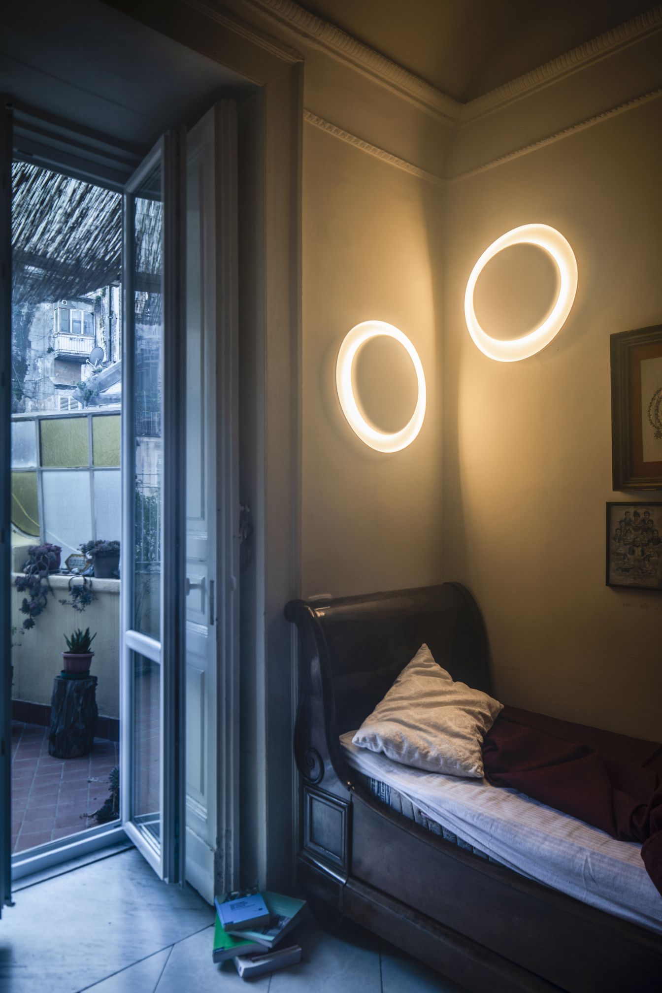 Zwei runde Bahia Mini Wandleuchten von Foscarini an der Wand über einem antiken Bett.