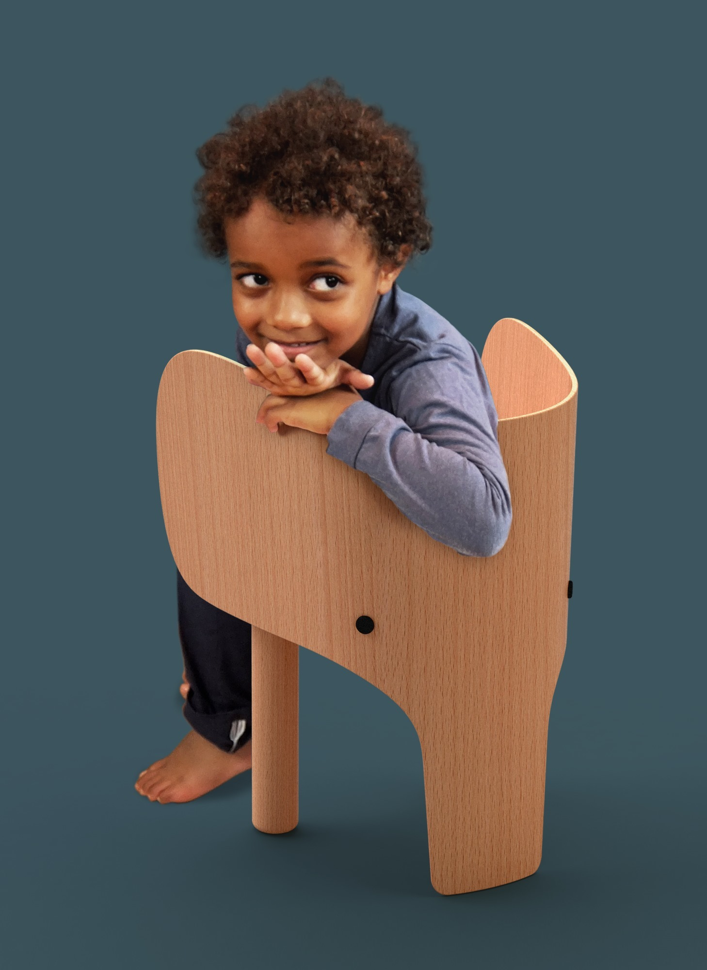 Junge lehnt lächelnd im hellen Holzstuhl in Elefantenform. Kinderstuhl, Designstuhl, EO.