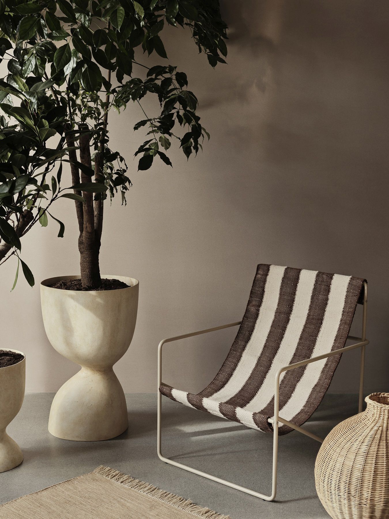 Ferm Living Desert Chair Loungesessel mit braun-weiß gestreiftem Stoffbezug und beigefarbenem Metallgestell.