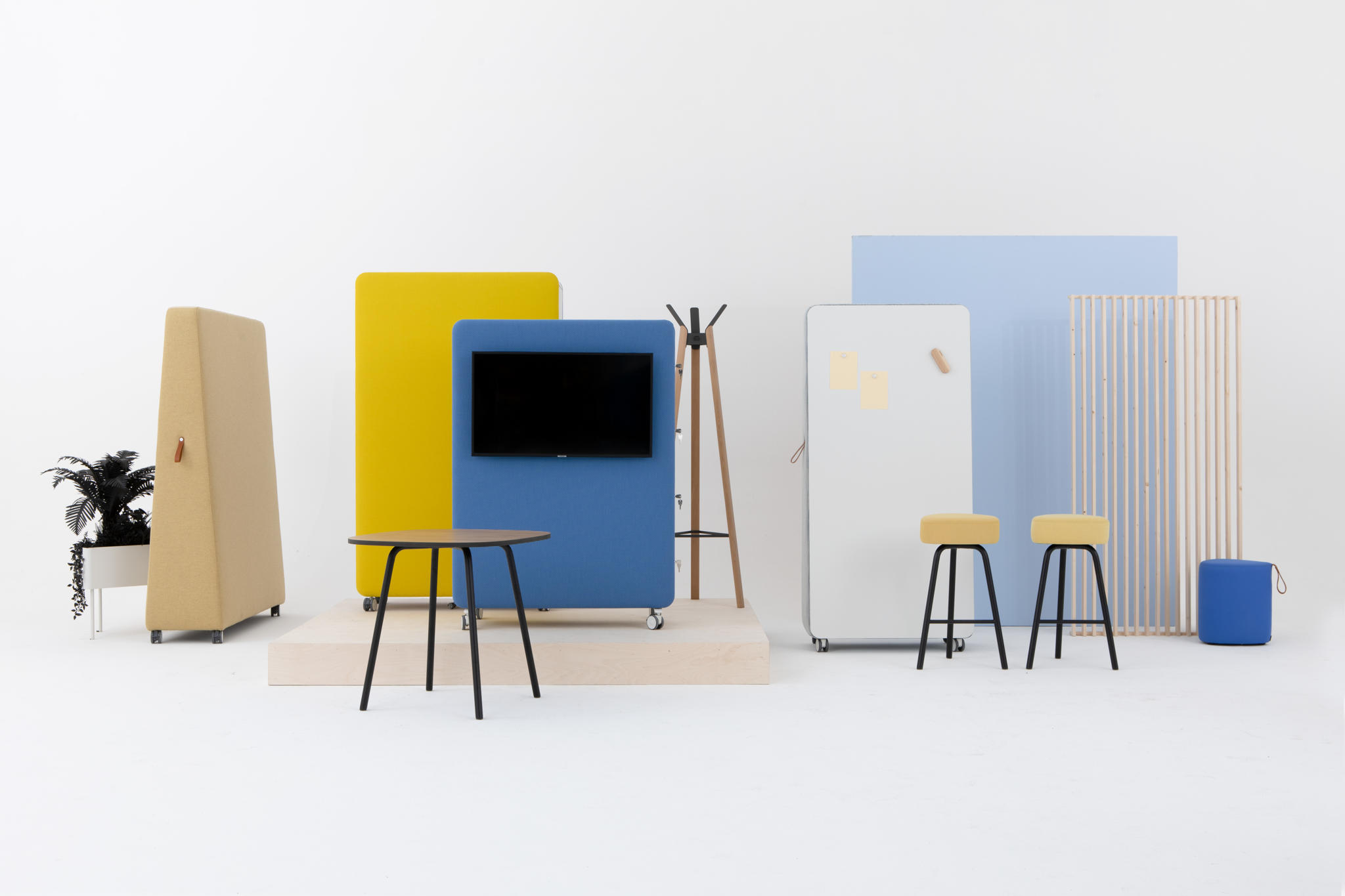 Cascando Pillow Space Akustik-Raumteiler in Gelb, Blau und Beige mit Tisch, Hocker und Garderobe.