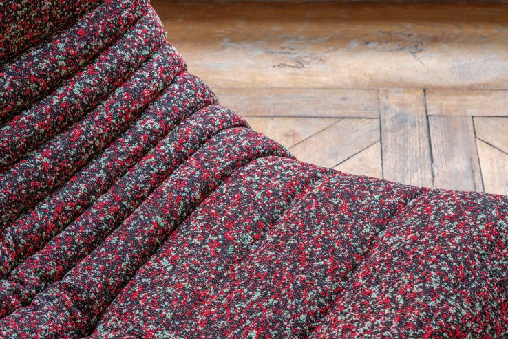 Detailaufnahme des roten Togo Sessel ligne roset mit Cordbezug und Holzboden im Hintergrund.