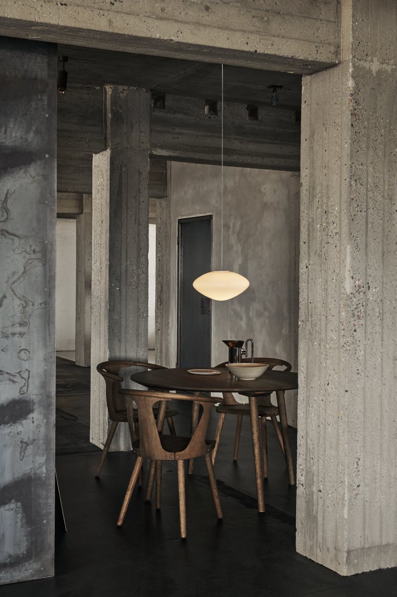 AndTradition Mist Pendelleuchte aus Opalglas über Esstisch mit Holzstühlen in modernem Interieur.