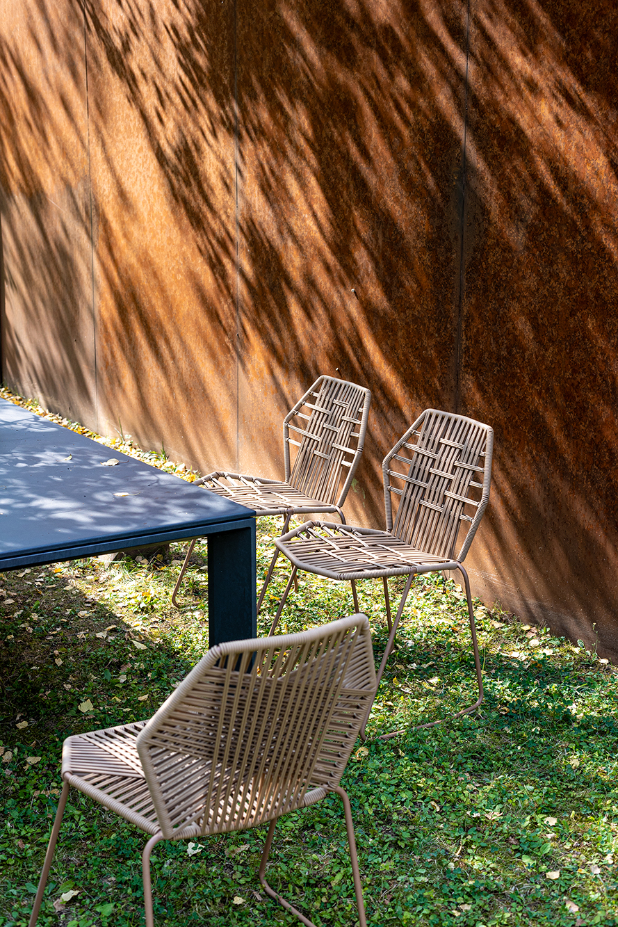Drei Tropicalia TR0 Outdoor Stühle aus Polymer von Moroso neben einem Tisch im Garten.