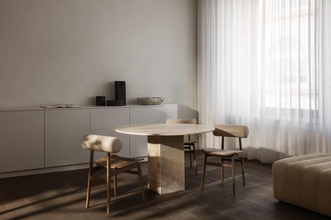 Esszimmer mit rundem Tisch und NORR11 Totem Stühlen mit beiger Polsterung und Holzgestell.