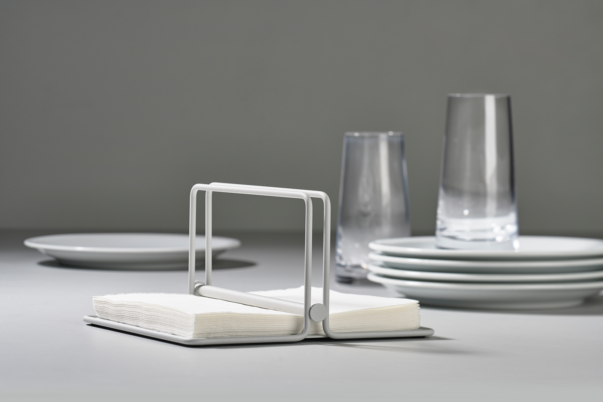 Weißer Serviettenhalter "Singles" von Zone Denmark mit Servietten auf einem Tisch mit Geschirr.