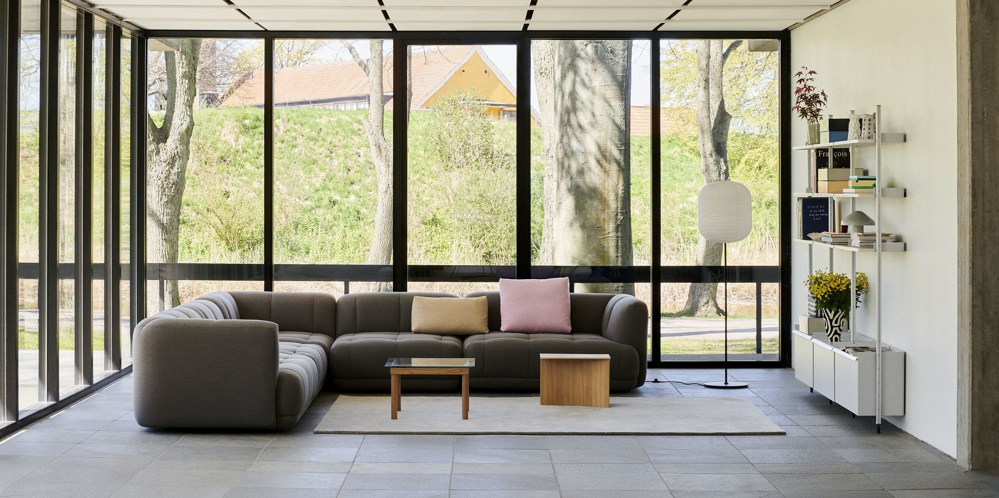 Helles Wohnzimmer mit großem Fenster und weißem Hay Pier System Regal mit drei Säulen.