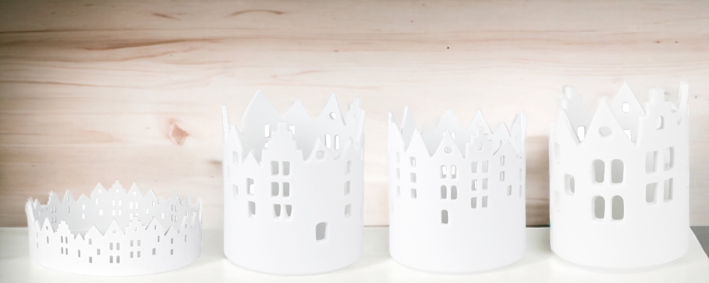 Zuhause Lichthaus Sortiment: Vier weiße Räder Stadtlichter Teelichthalter aus Porzellan mit Hausmotiven.