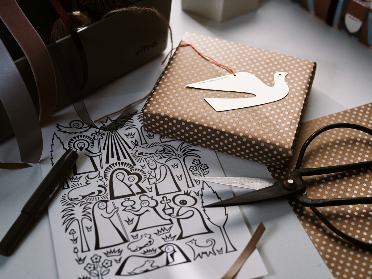 Geschenk mit Taubenanhänger, Schere, Stift und Weihnachtsmotiv-Papier zum Basteln und Verpacken von Weihnachtsgeschenken.