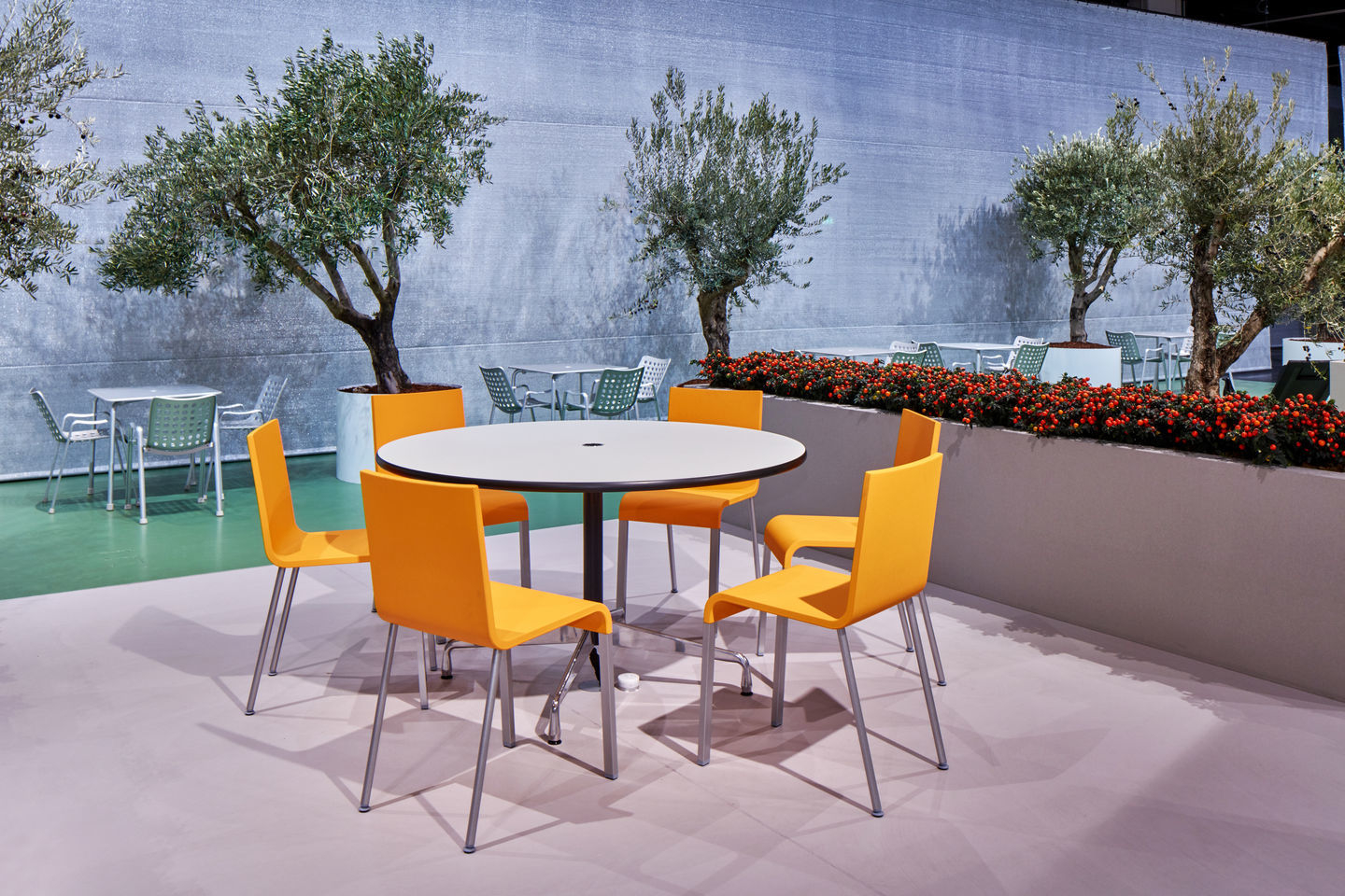 .03 Stuhl von Vitra in Orange um einen runden Tisch im Außenbereich.