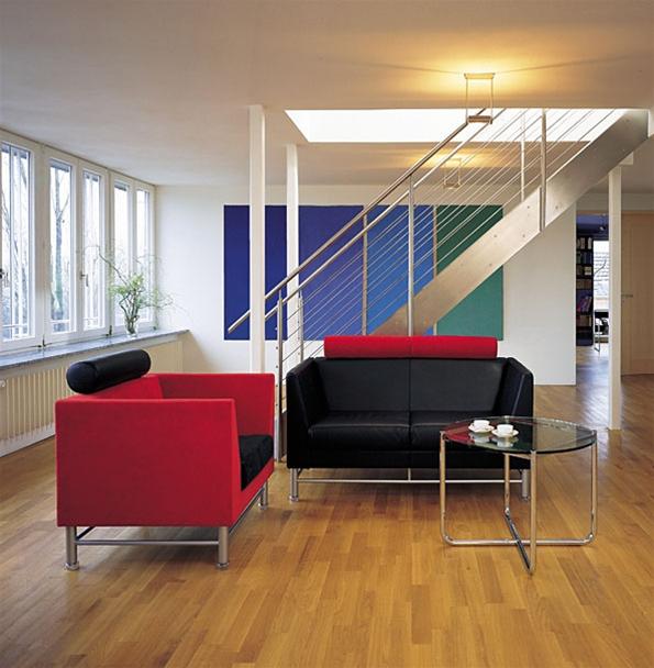 Wohnzimmer mit rotem Sessel, schwarzem Sofa und rundem MR Couchtisch von Knoll International.