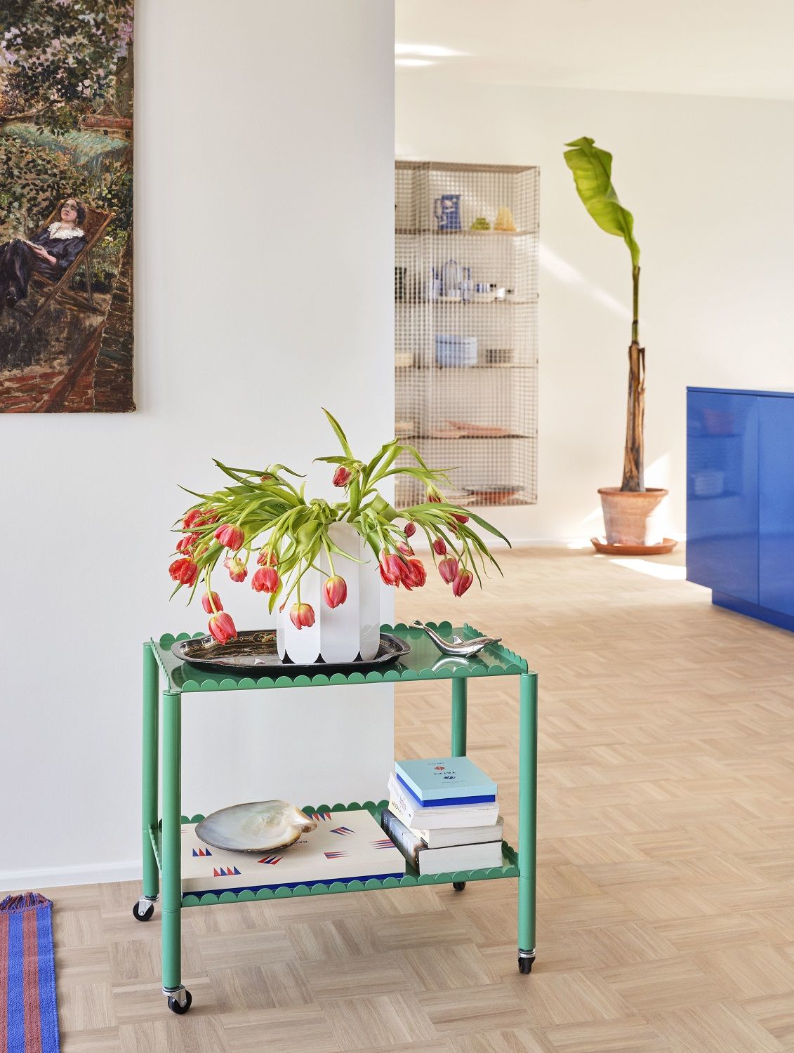 Grüner Arcs Trolley Servierwagen von Hay mit Tulpen, Büchern und Dekoration in einem hellen Raum.