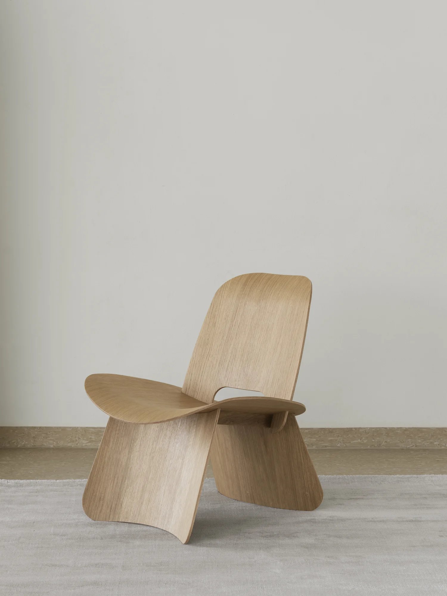 Nagomi Chair von Blomus: Moderner Holzstuhl mit minimalistischem Design und skulpturaler Form auf Teppich.