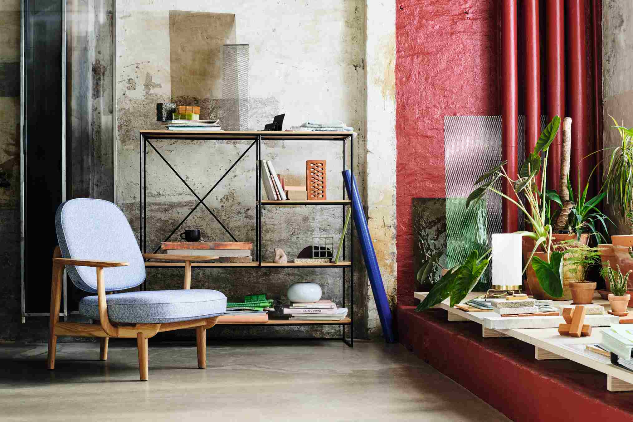 Fritz Hansen Fred Loungesessel mit hellblauem Bezug und Holzgestell vor Bücherregal und Pflanzen.
