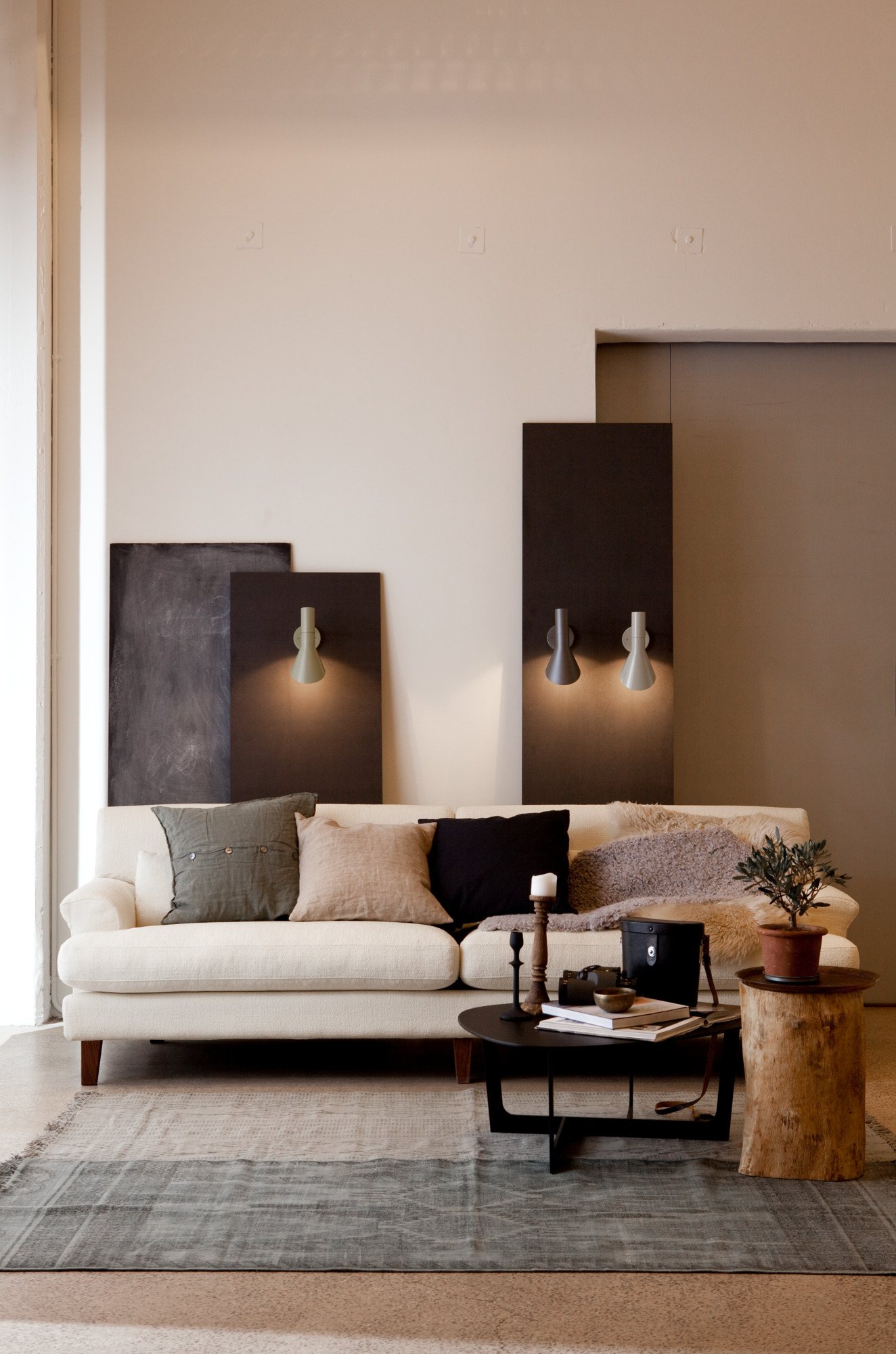 Gemütliches Wohnzimmer mit beigem Sofa, Couchtisch, Teppich und Wandlampen für stilvolles Wohnen.