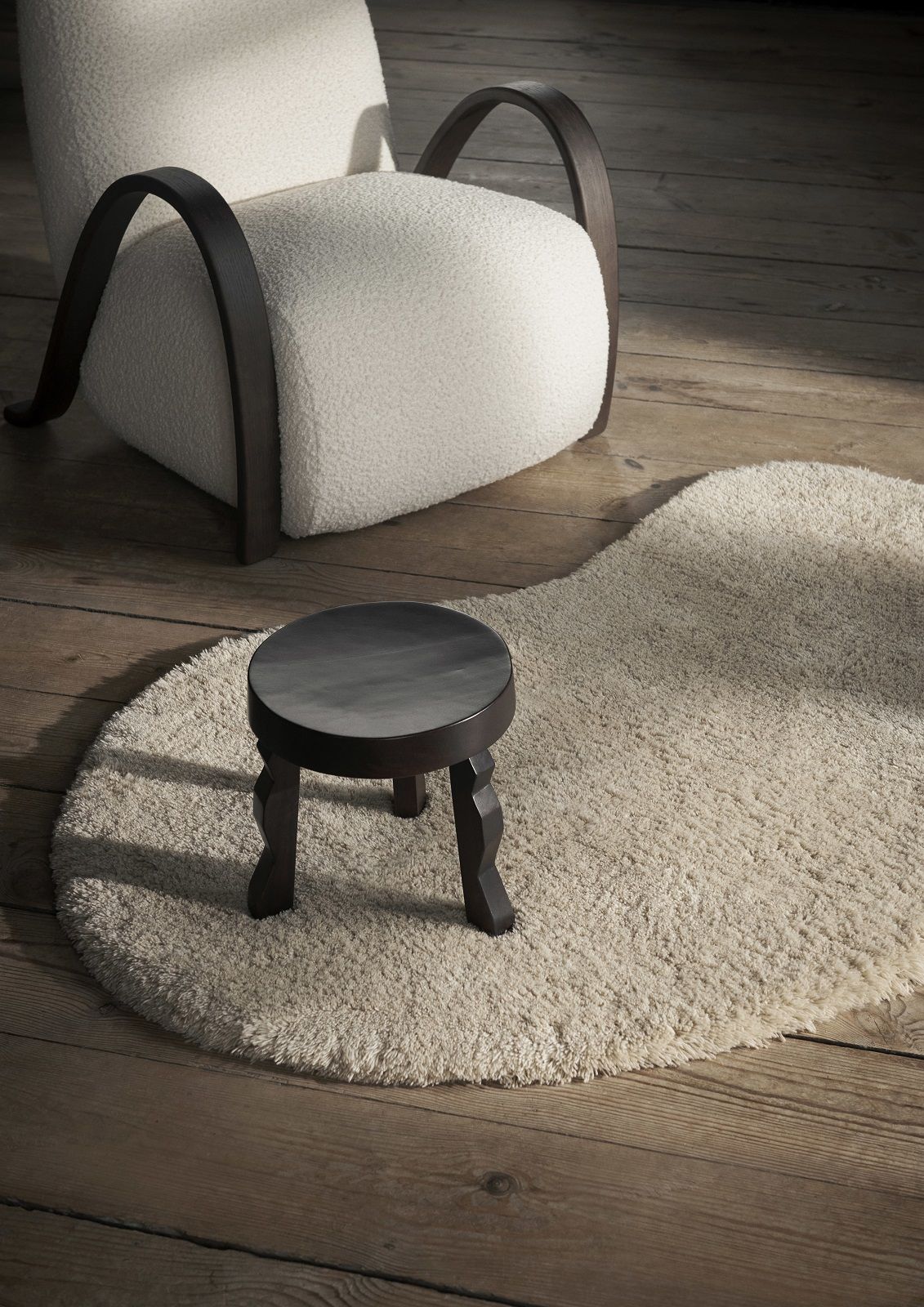 Buur Lounge Chair von Ferm Living mit Hocker und Teppich auf Holzboden.