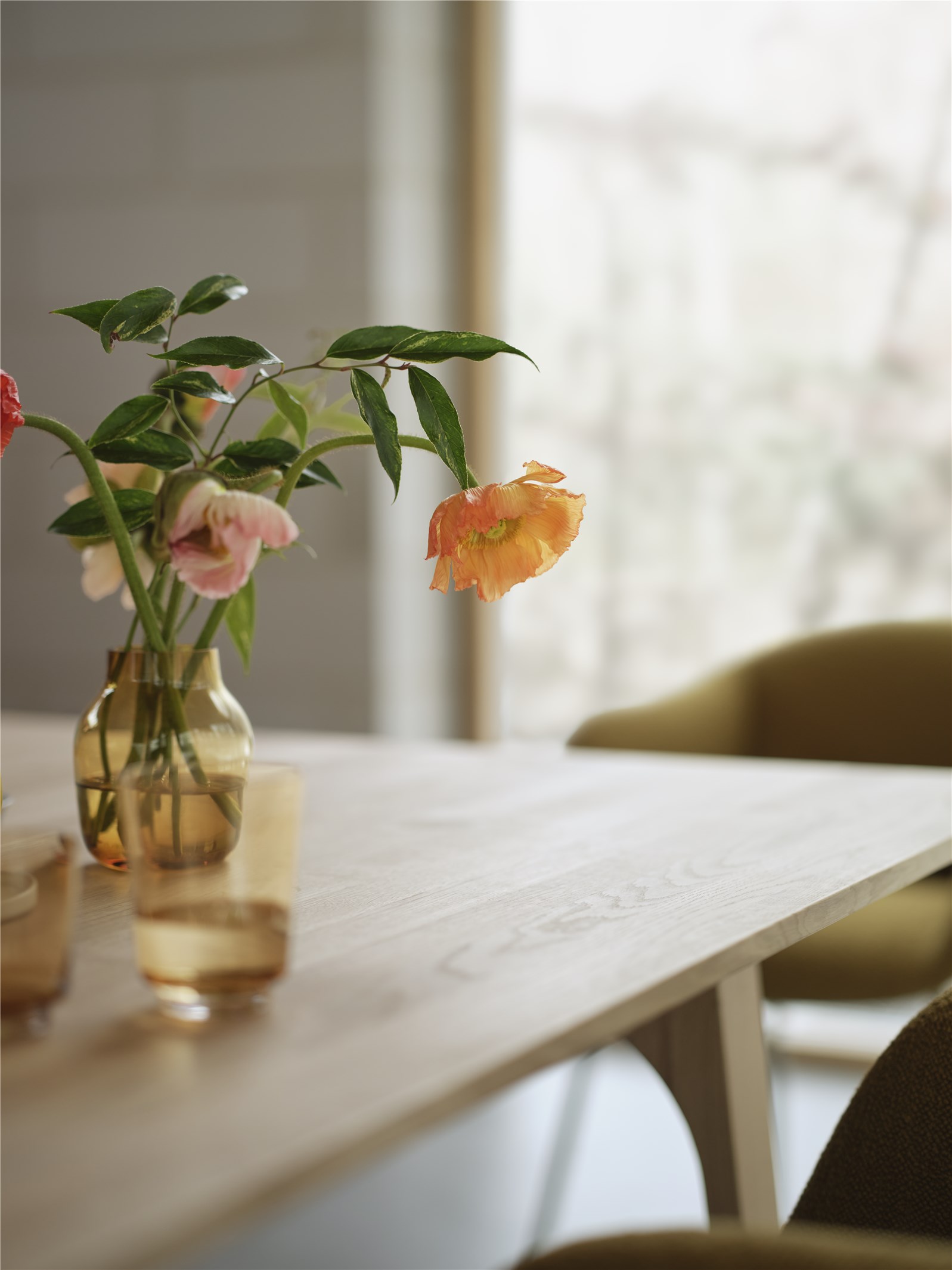 Nahaufnahme des Earnest Esstisches von Muuto mit Blumen in Vasen und Stühlen.