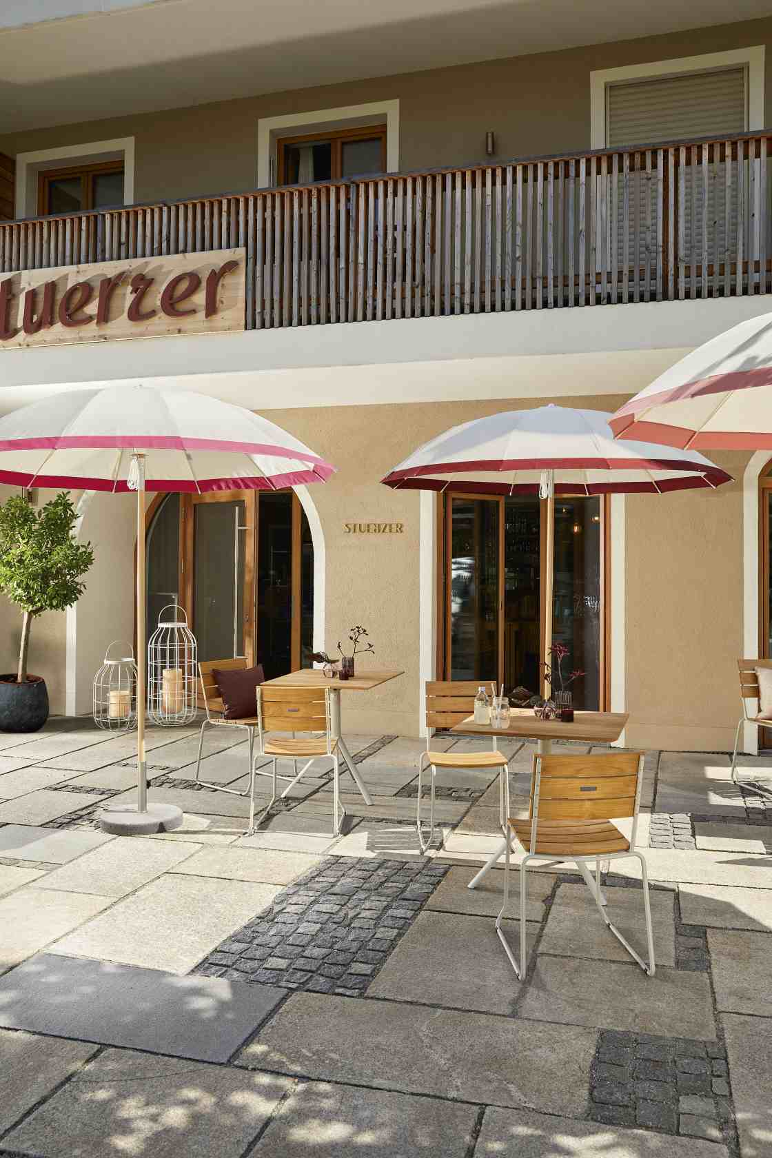 Weishäupl Pagodenschirm: Sonnenschirme mit Tischen und Stühlen vor einem Gebäude, ideal für Gastronomie und Garten.