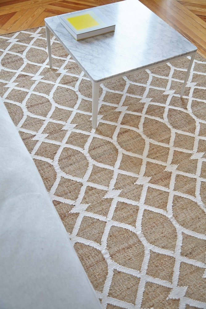 Detailaufnahme des GAN Kilim Rodas Teppichs mit geometrischem Muster in Beige und Weiß unter einem Tisch.