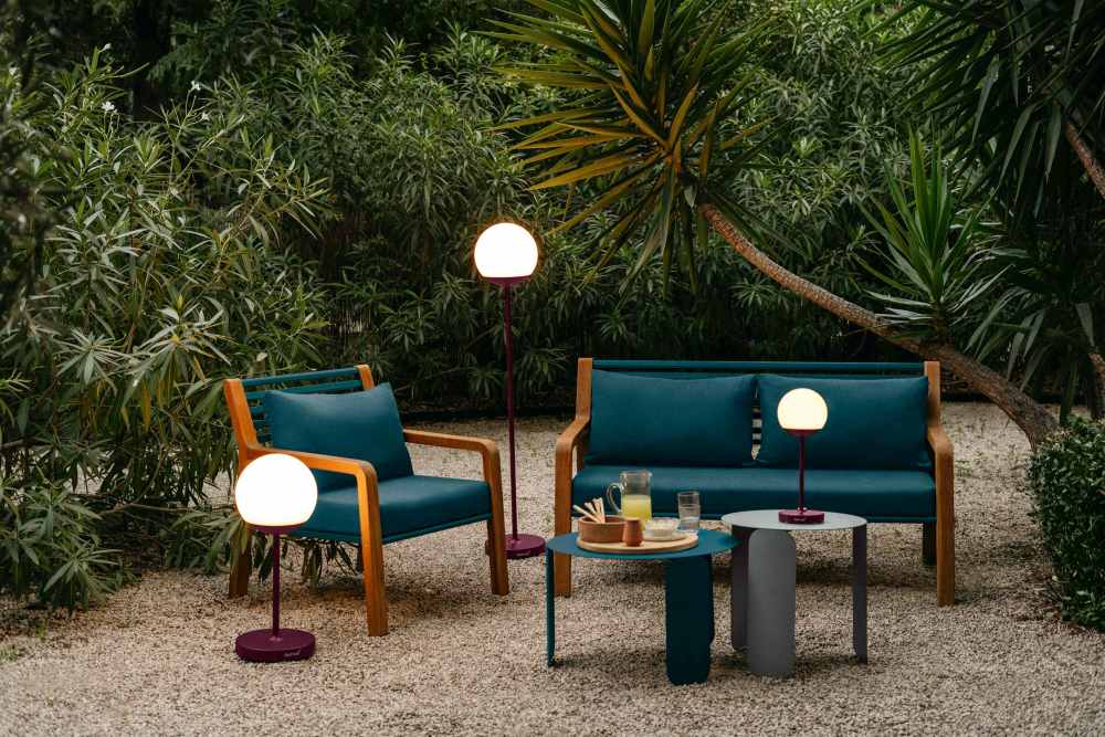Fermob Somerset Sofa, Sessel und Gartentische in Szene gesetzt mit modernen Kugellampen im Garten.