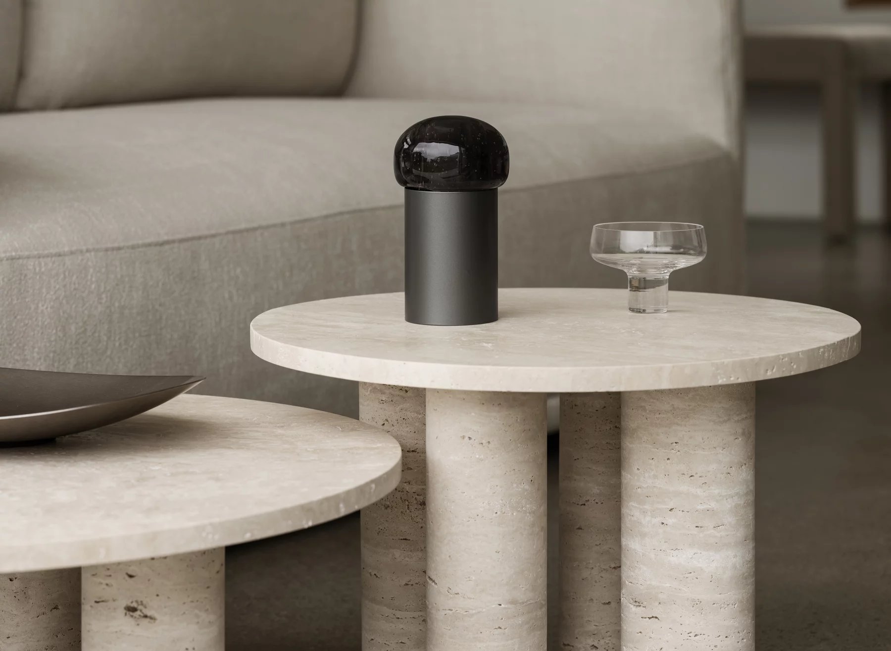 Blomus Volos Couchtisch rund, beige Travertin mit drei zylindrischen Beinen, modernes Wohnzimmer-Interieur.