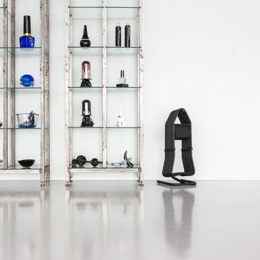 Schwarzer Kleiderbügelständer aus Metall mit zwei Vitrinen im Hintergrund, modernes Design für Garderobe und Ankleidezimmer.
