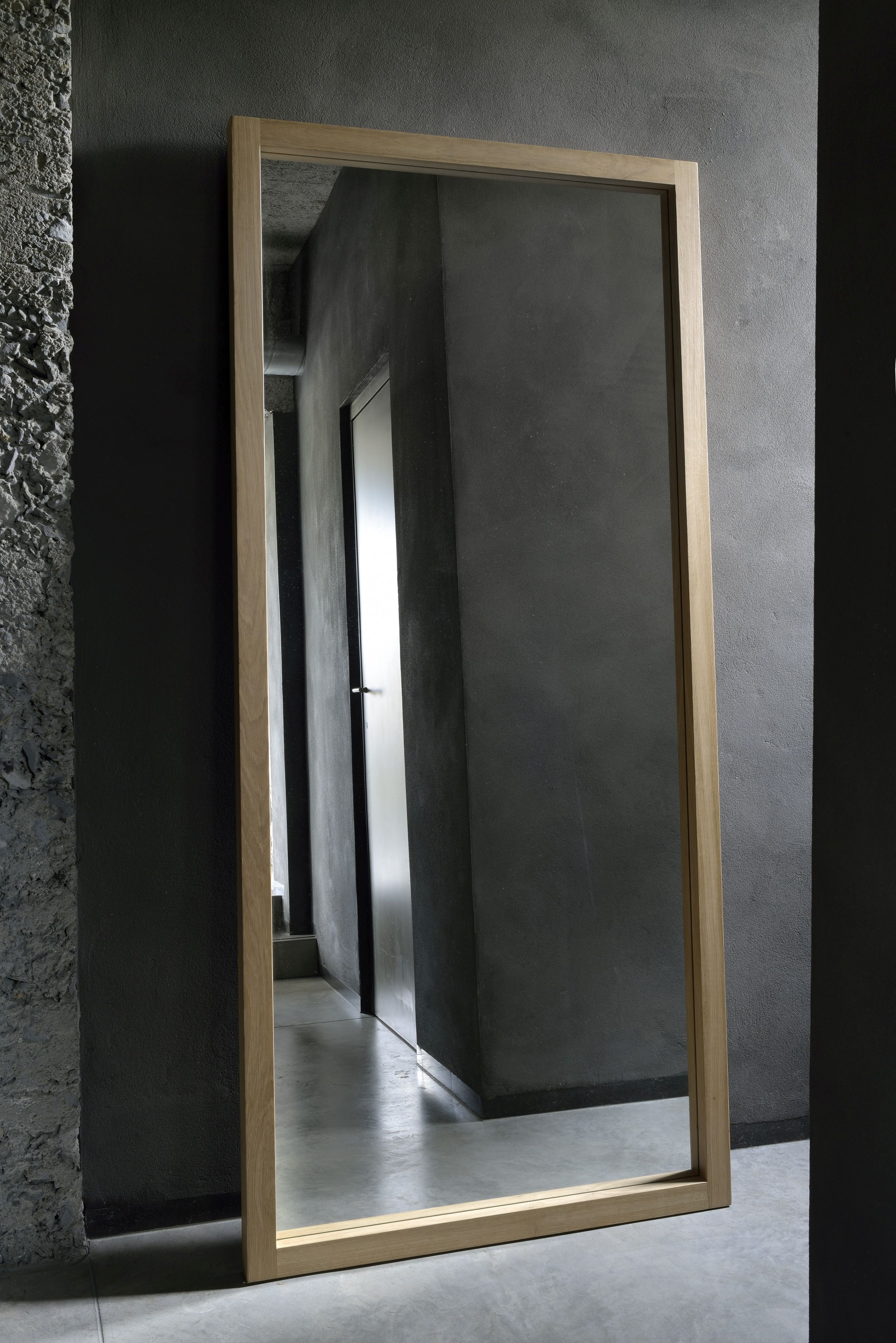 Light Frame Spiegel von Ethnicraft: Rechteckiger Spiegel mit hellem Eichenholzrahmen, stehend an grauer Wand.
