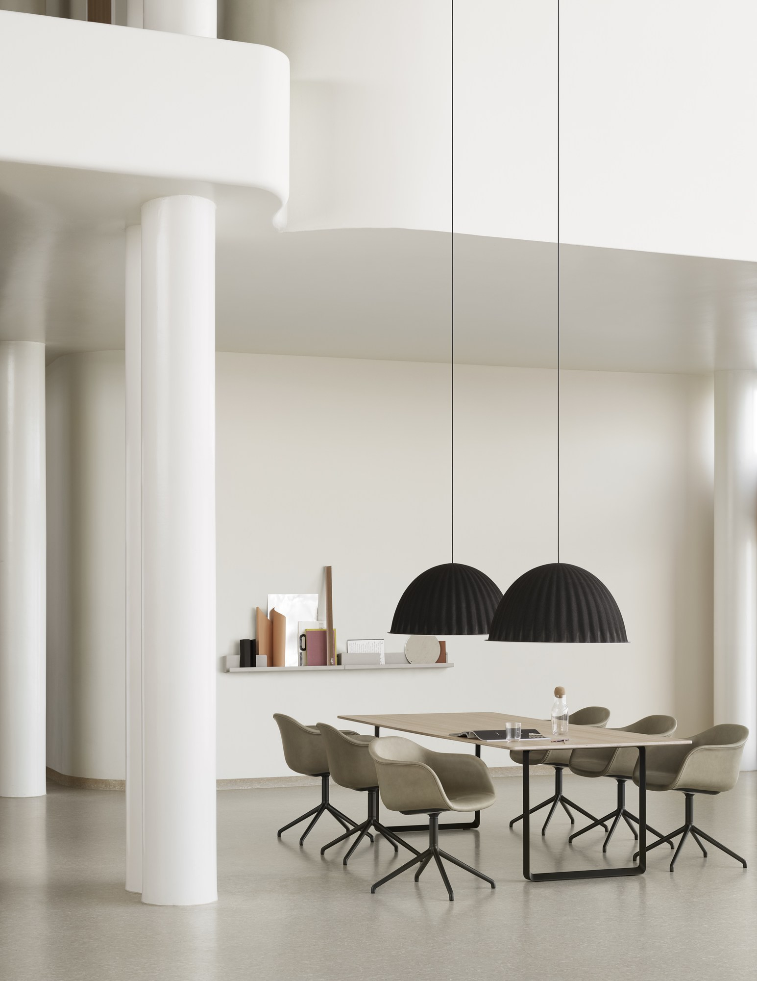 Helle Raumszene mit Esstisch, Stühlen und zwei schwarzen Under The Bell Pendelleuchten von Muuto.