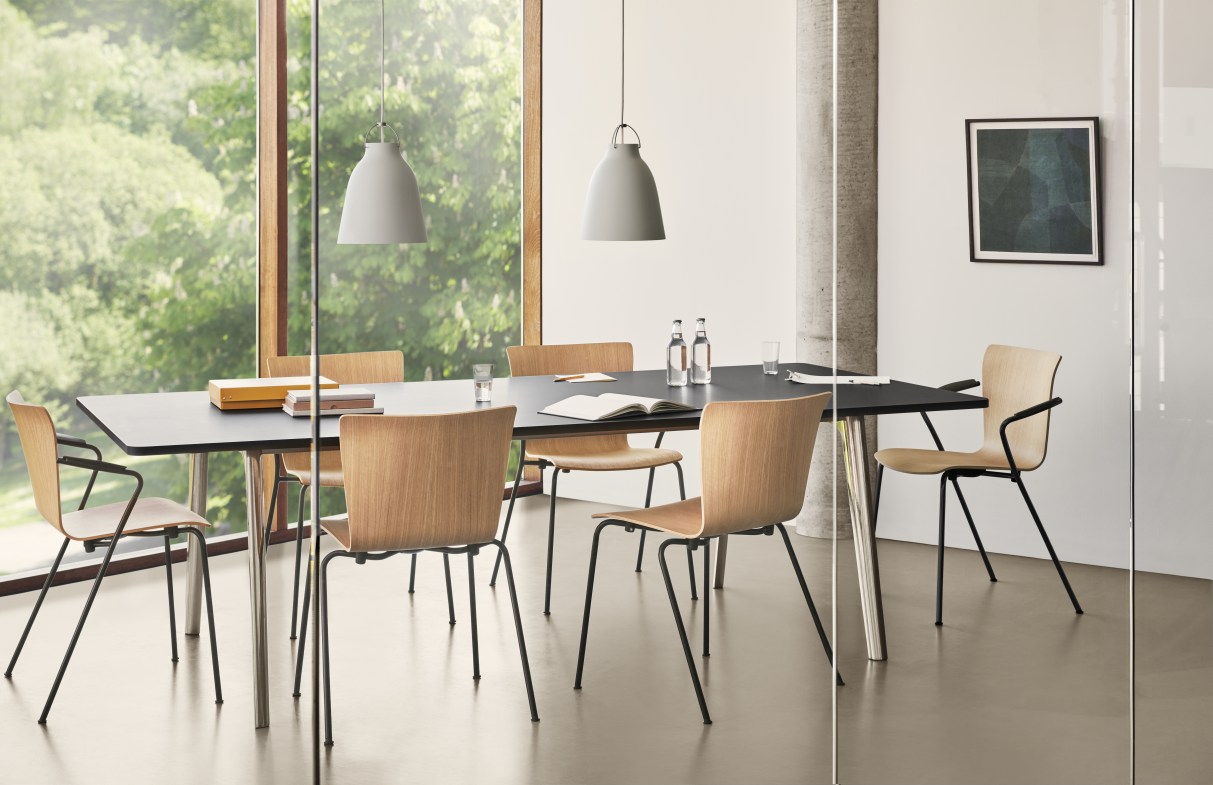 Helles Büro mit schwarzem Tisch, Holzstühlen und zwei grauen Caravaggio Pendelleuchten von Fritz Hansen.