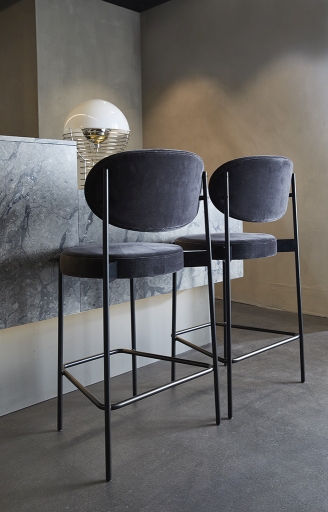 Zwei graue Verpan Series 430 Barhocker mit schwarzem Gestell und Fußstütze vor einer Küchentheke.