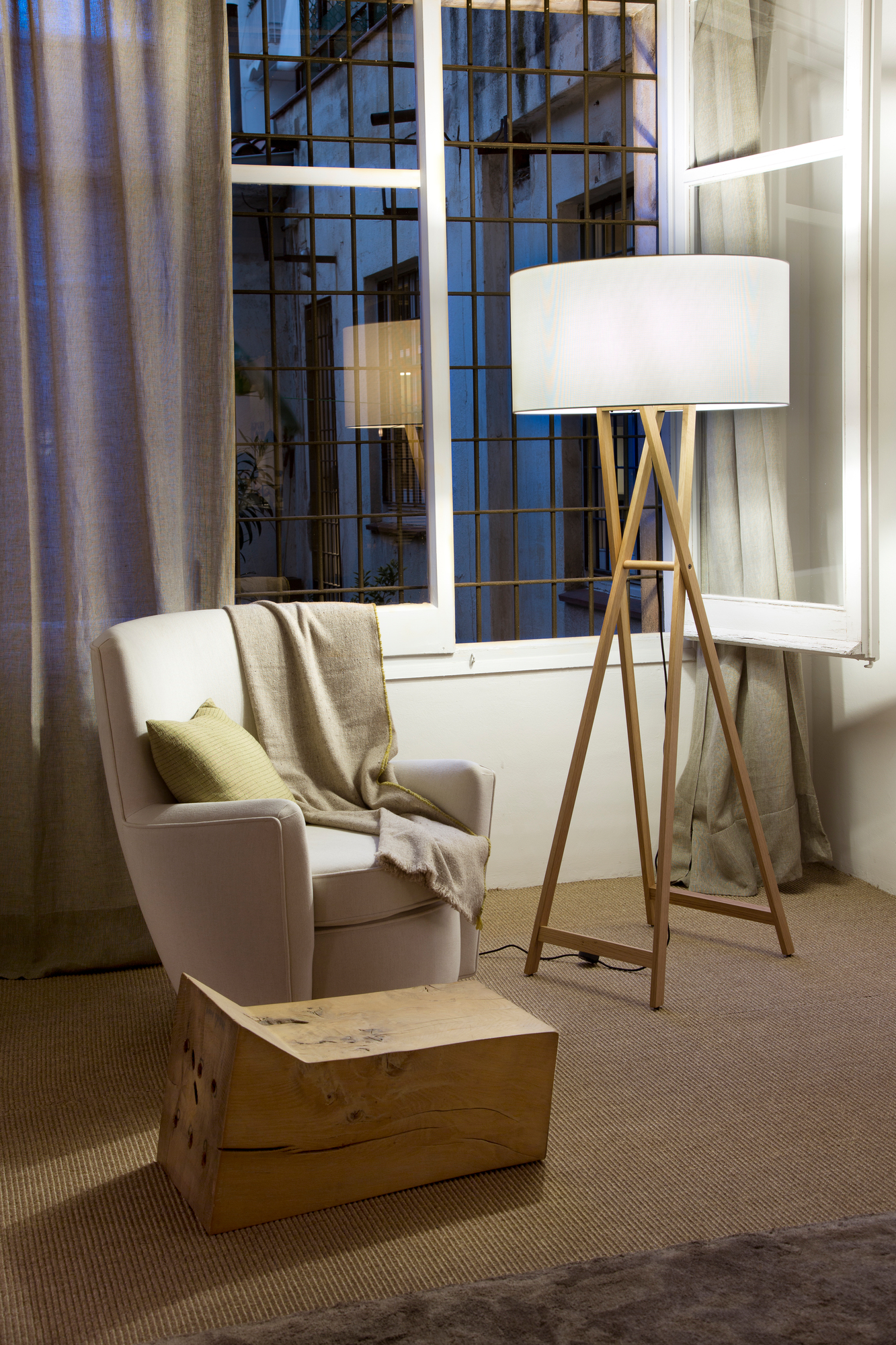 Cala Stehleuchte von Marset: Moderne LED-Lampe mit Holzgestell neben Sessel im Wohnzimmer.