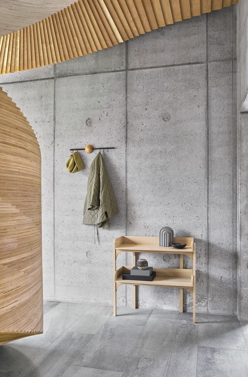 Helles Woud Utility Regal aus Holz mit zwei Ablageflächen vor einer Betonwand.