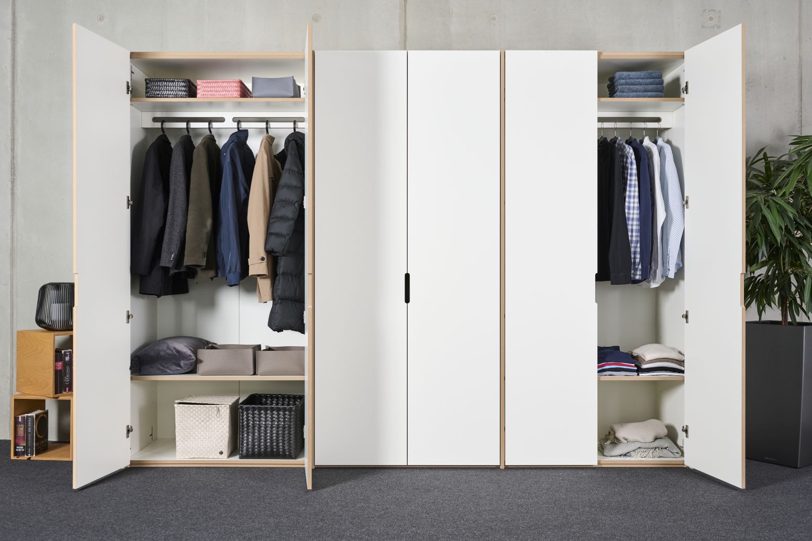 Tojo Schrank Grundmodul: Weißer Kleiderschrank mit offenen Türen, Kleidung auf Bügeln und Regalen.