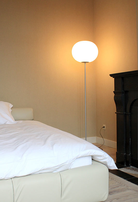 Glo Ball Stehleuchte von Flos neben einem Bett und einem Kamin im Schlafzimmer.