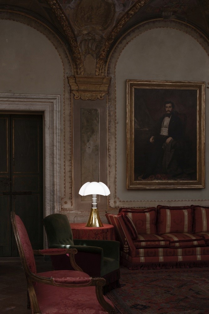 Pipistrello Tischleuchte von Martinelli Luce auf rotem Tisch in klassischem Interieur mit Sofa und Gemälde.