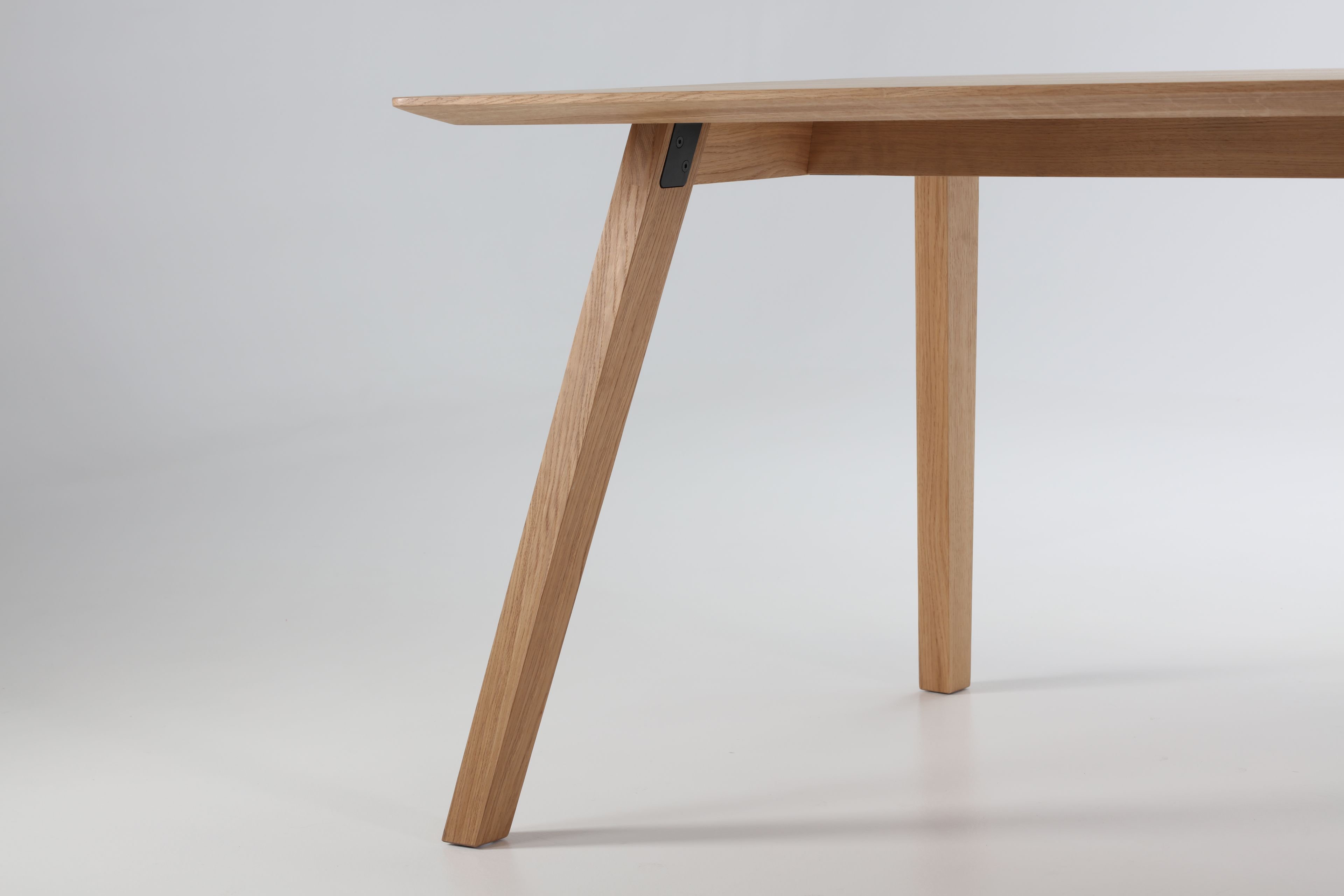 Detailaufnahme des Prostoria Monk Tisches mit hellen Holzbeinen und minimalistischem Design vor neutralem Hintergrund.