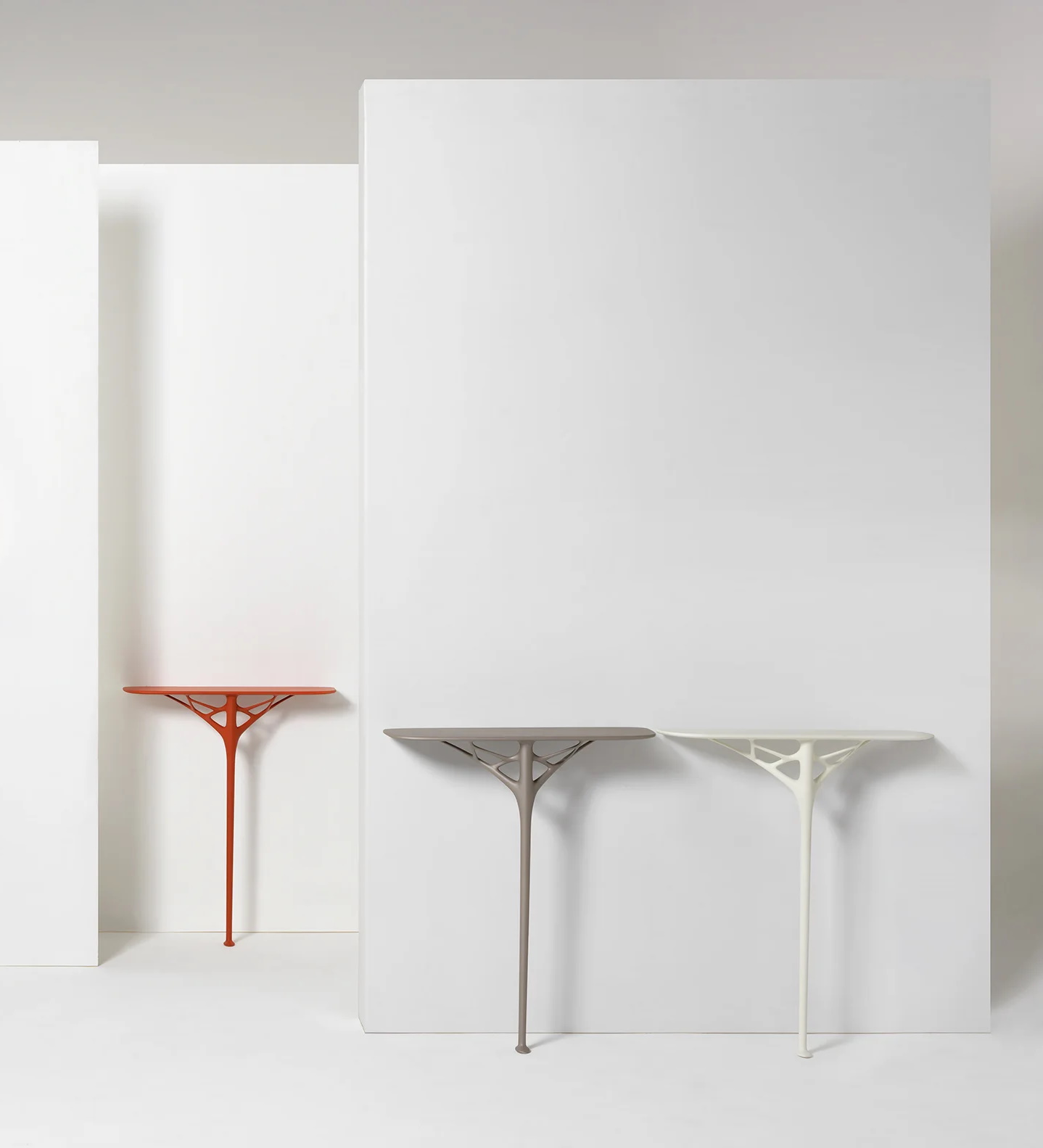 A.I. Console von Kartell: Drei Konsolentische in Orange, Grau und Weiß vor weißem Hintergrund.