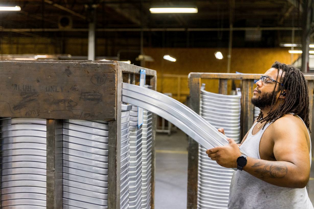 Mann entnimmt Aluminium-Rückenlehnen für Emeco Navy Chair Stühle aus einer Holzkiste in einer Fabrik.