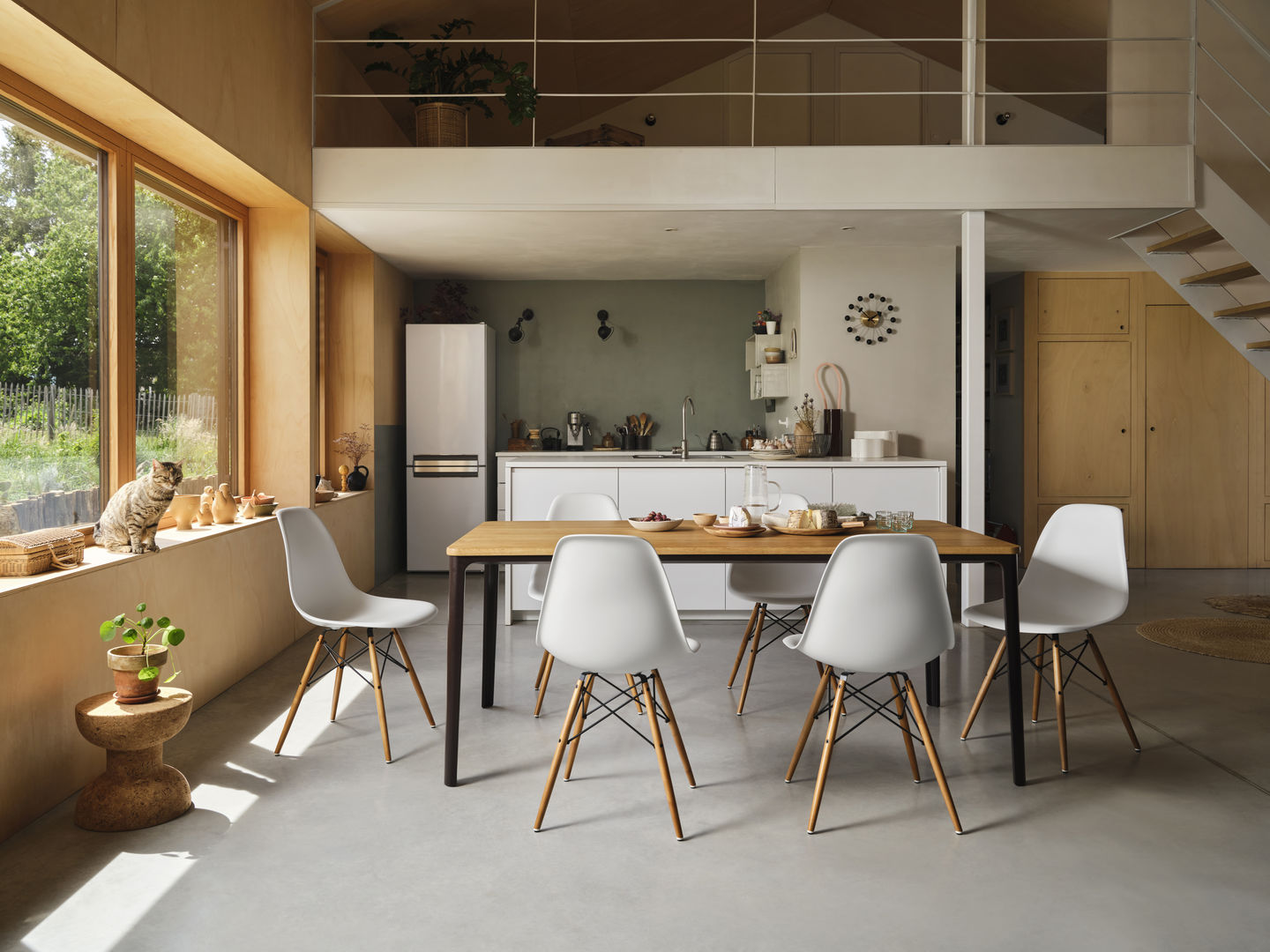 Helle Esszene mit Vitra Eames DSW Stühlen mit Sitzpolster in Weiß um einen Holztisch.