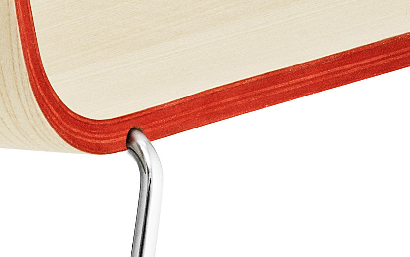 Detailaufnahme vom Normann Copenhagen Just Chair: Sitzfläche aus hellem Holz mit rotem Rand und Chromfuß.