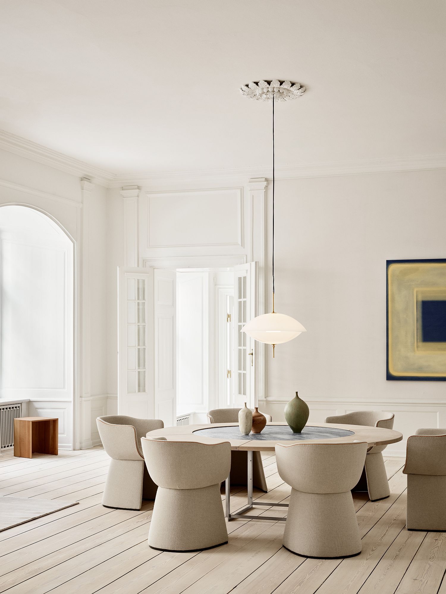 Innenaufnahme eines Esszimmers mit rundem Tisch und Monolit Stühlen von Fritz Hansen in Beige.