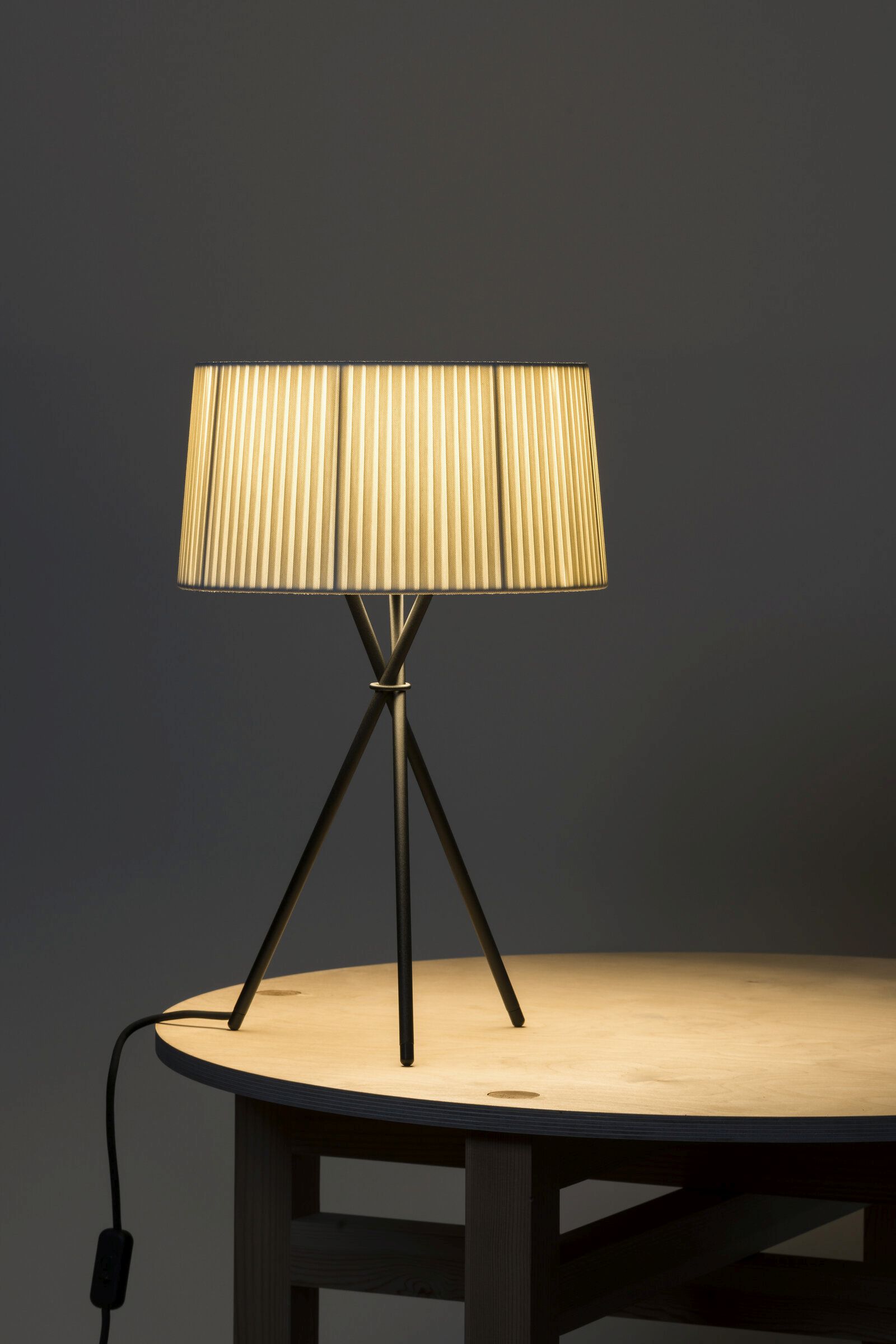 Tripode M3 Tischleuchte Diplomática stripe von Santa & Cole auf einem Holztisch, warmes Licht.